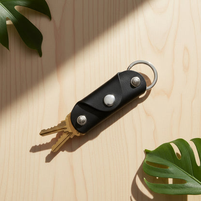 Black leather key organizer with keys on a white background