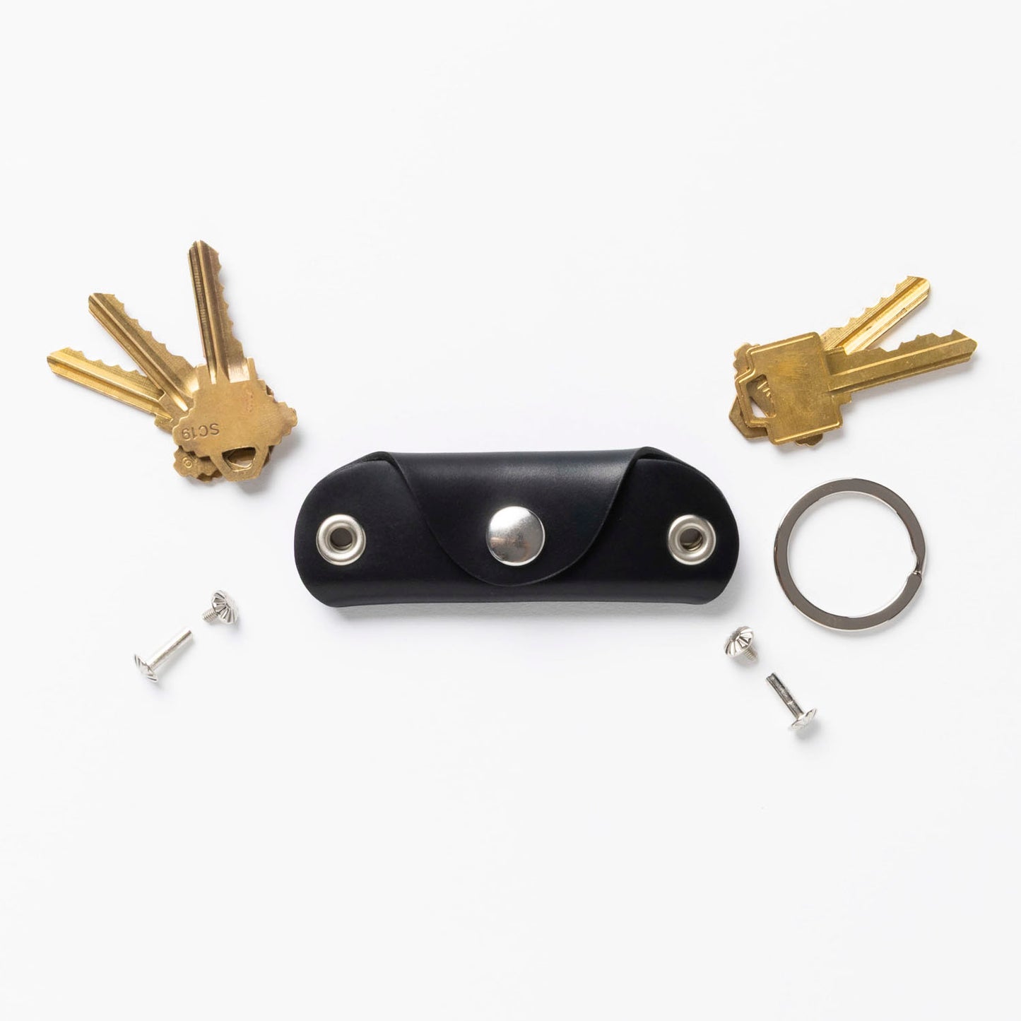 Black leather key holder with keys and tools on a white background