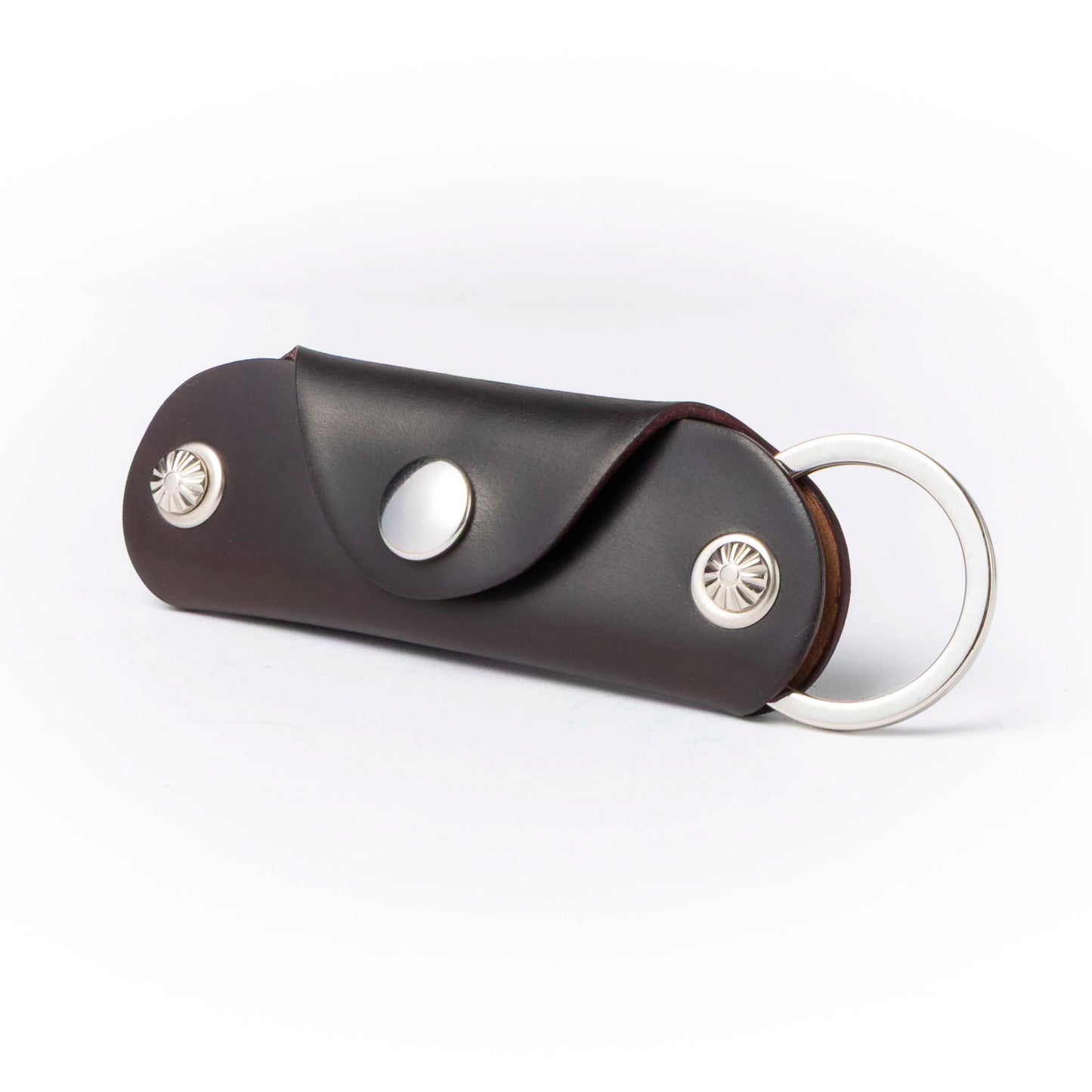 Brown leather key case with silver accents on a white background