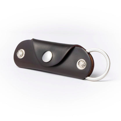 Brown leather key case with silver accents on a white background