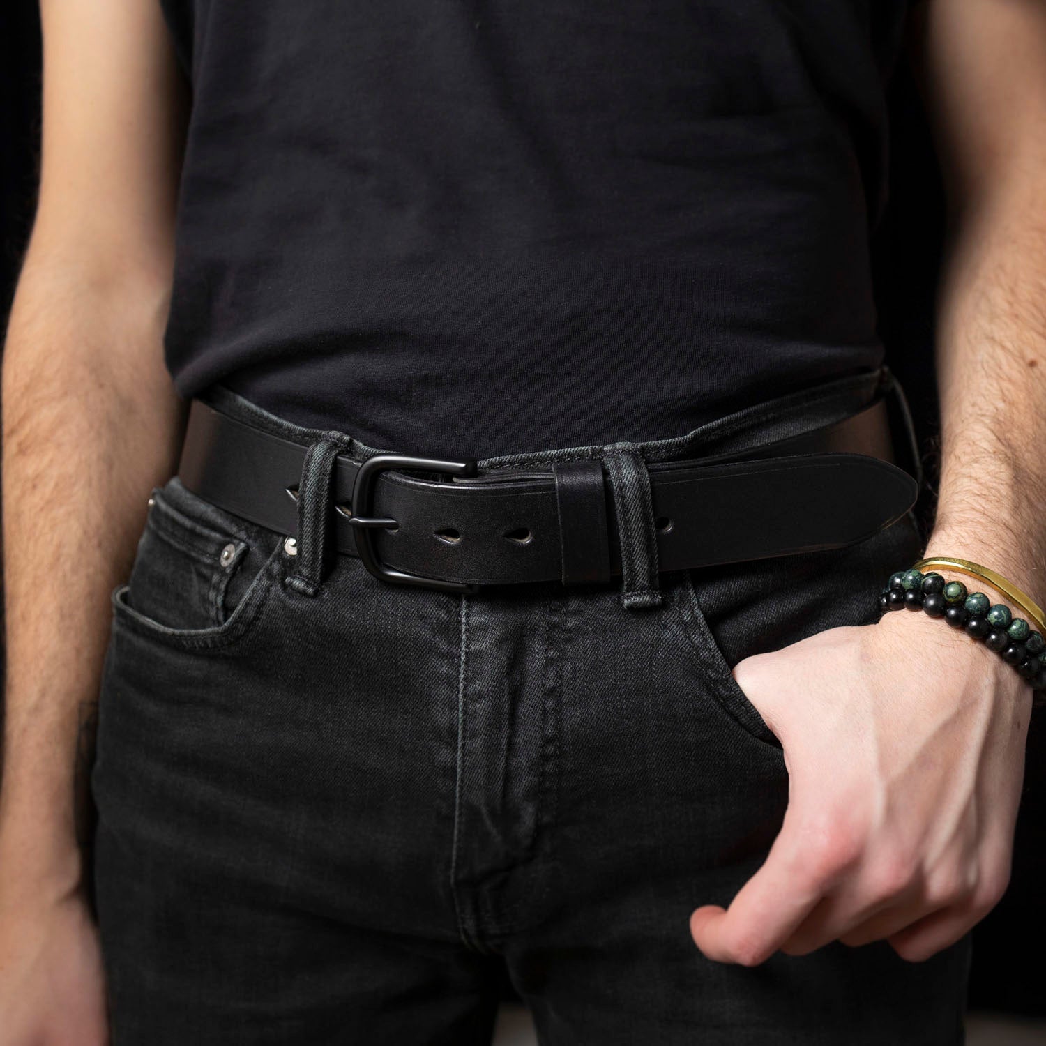Person wearing a black belt and black pants with a blurred background