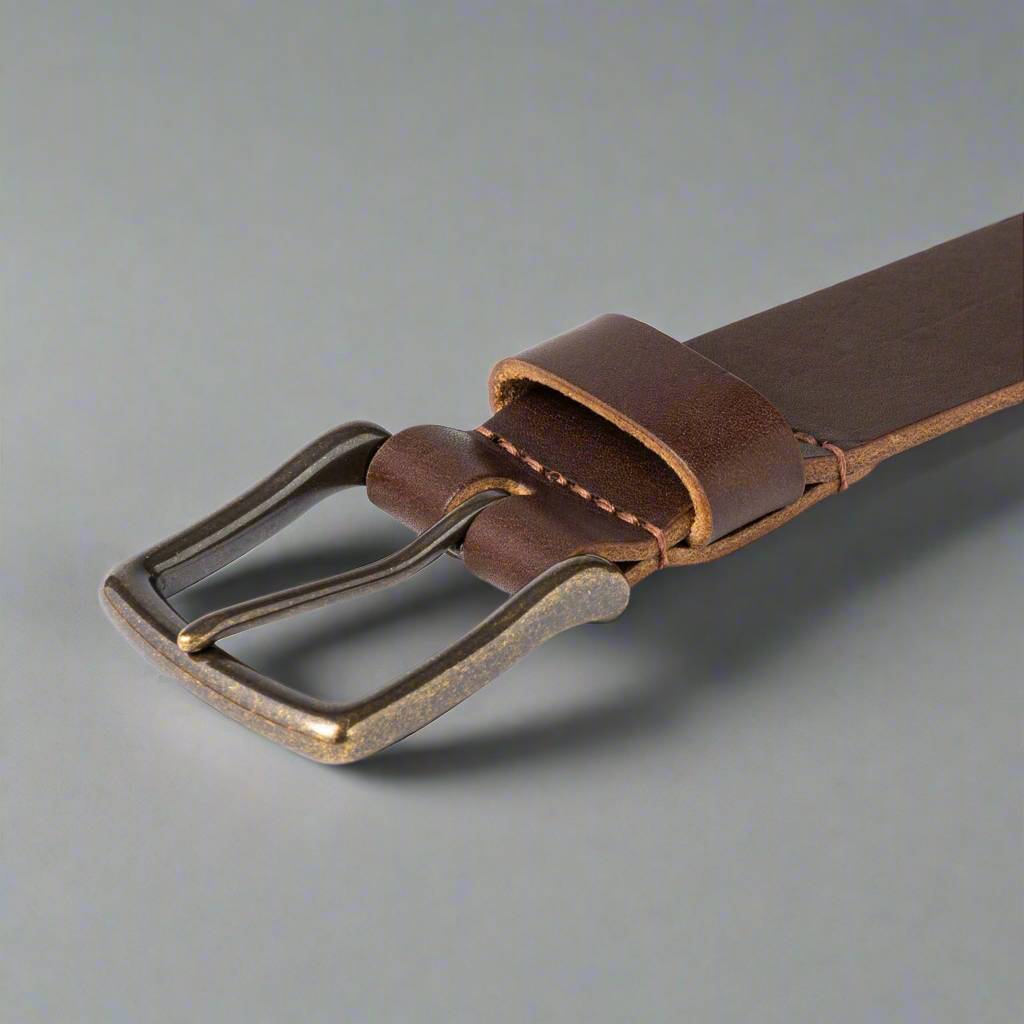 Brown leather belt with a brass buckle on a gray background