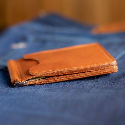 Capone Money Clip on a blue surface, showing edge detail of leather, with a blurred blue background